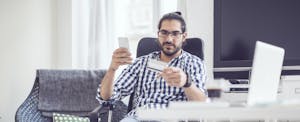 Man sitting in a chair, looking at a credit card